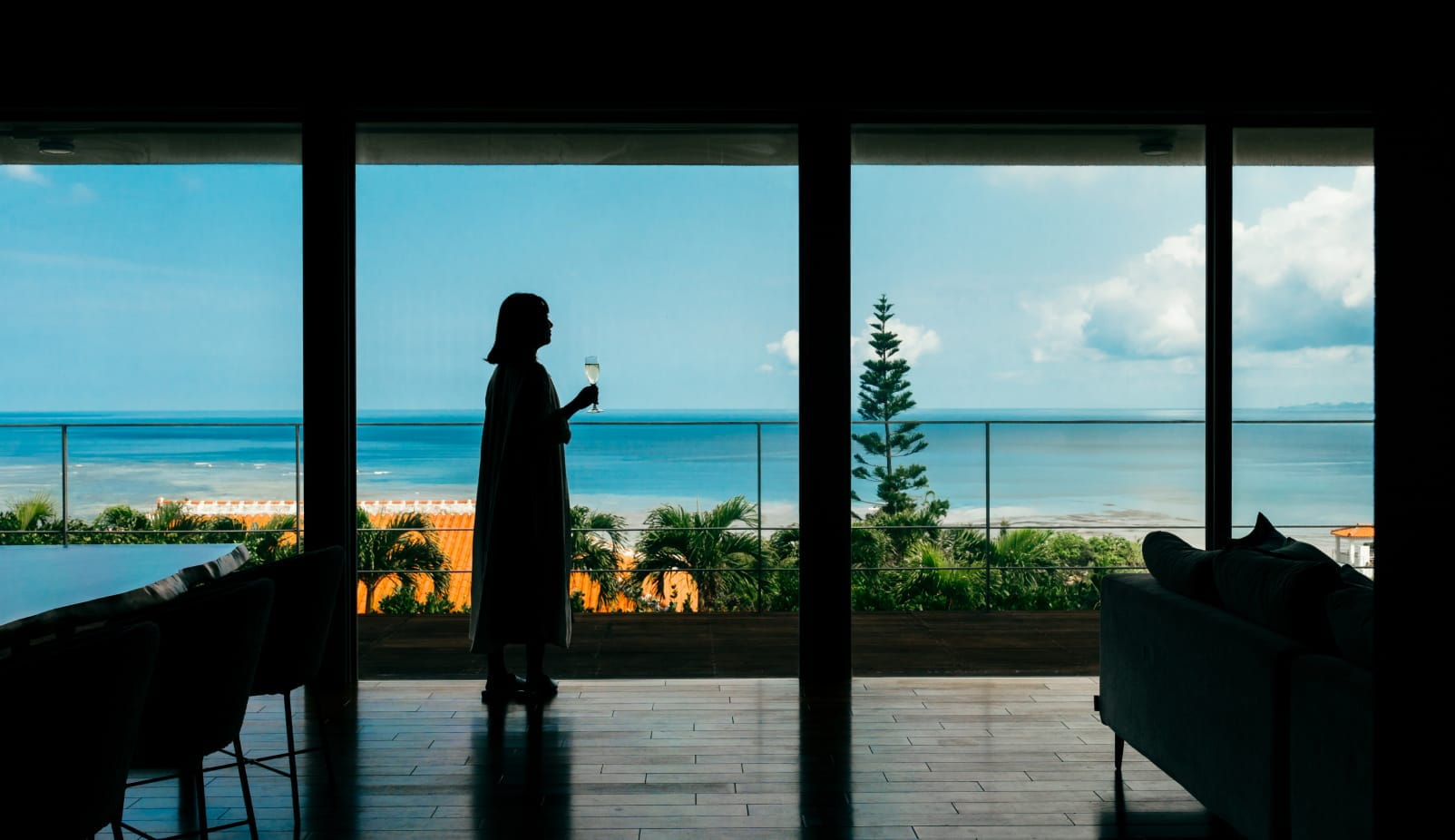 Woman holding glass while gazing at the sea at a luxury villa in Ishigaki Island